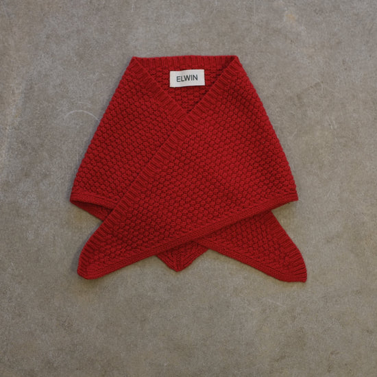 Red knitted scarf on a gray surface