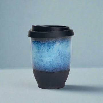 Blue and black ceramic cup on a light blue background