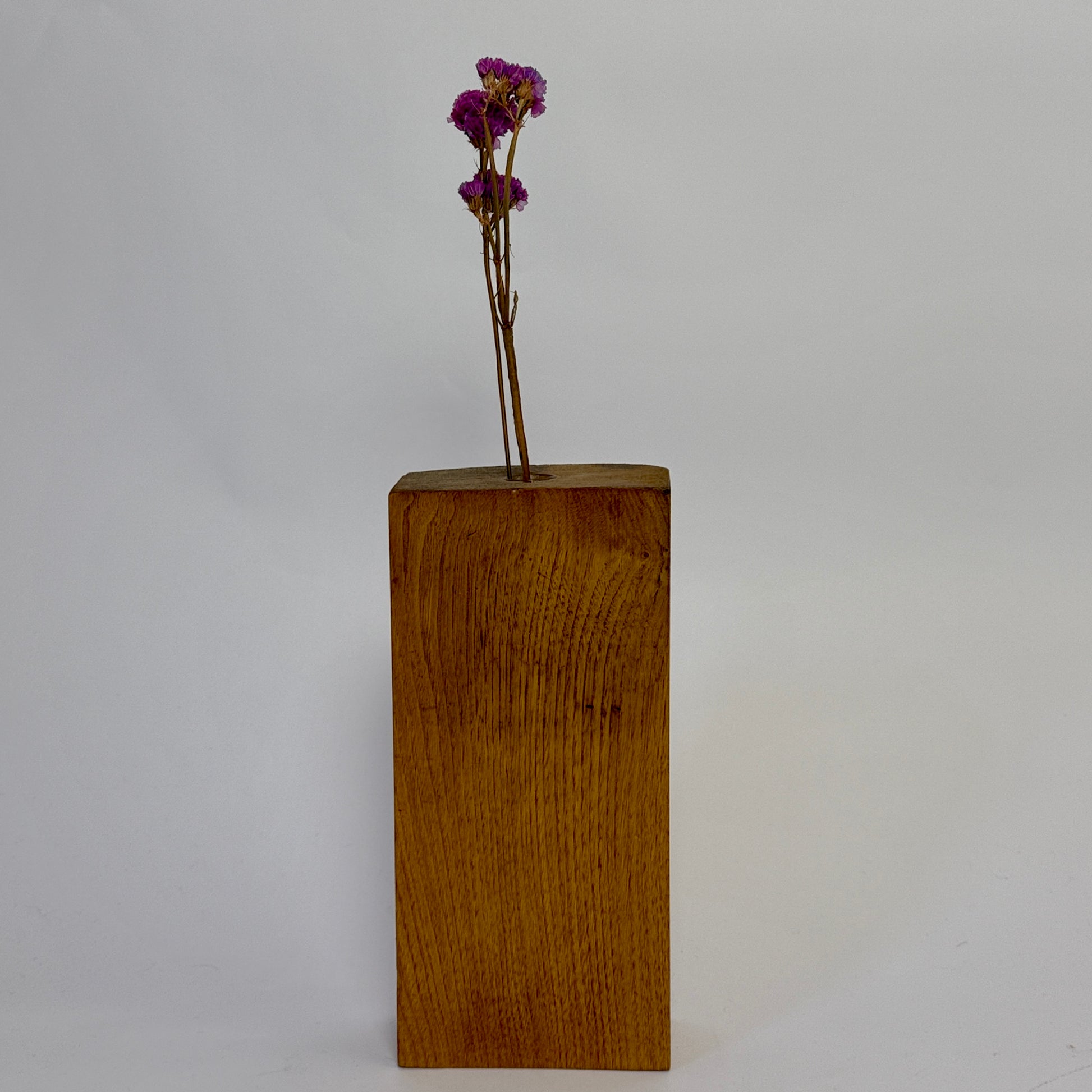 Wooden block with a small bouquet of purple flowers on a plain background