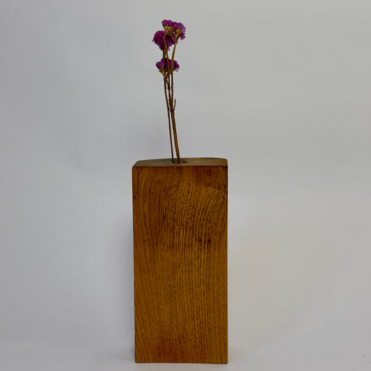Wooden block with a small bouquet of purple flowers on a plain background