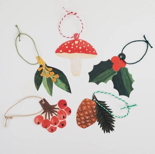 Set of Christmas-themed ornaments including a mushroom, holly, pine cone, and berries on a white background.