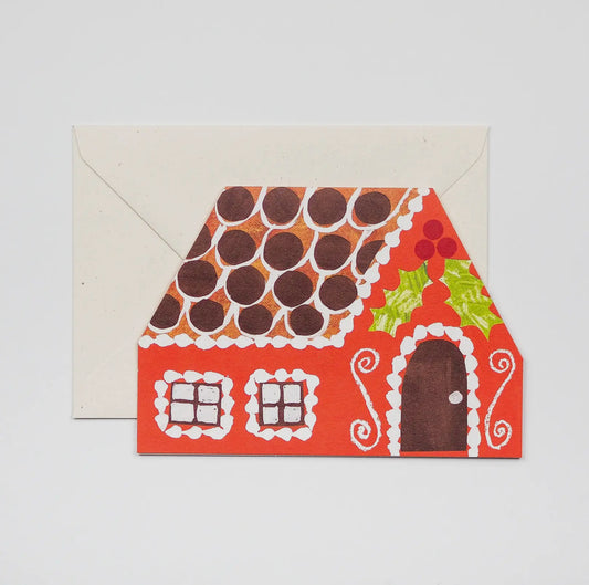 Gingerbread house-shaped card with a decorative envelope on a light gray background