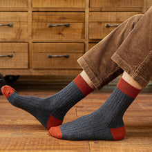 Load image into Gallery viewer, Person wearing grey and red ribbed socks with brown cord trousers in front of wooden furniture and a wooden floor
