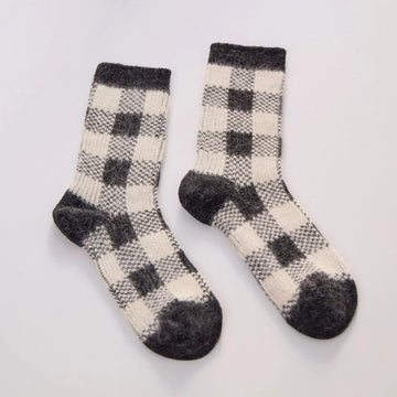 black and cream plaid socks in rabbit hair and wool on a grey background