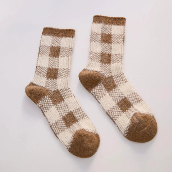 plaid brown and cream rabbit hair and wool socks laid out on a grey background