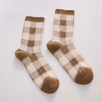 plaid brown and cream rabbit hair and wool socks laid out on a grey background