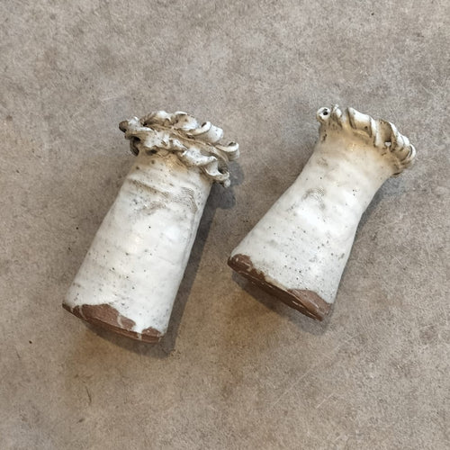 Two white ceramic vases on a gray concrete surface