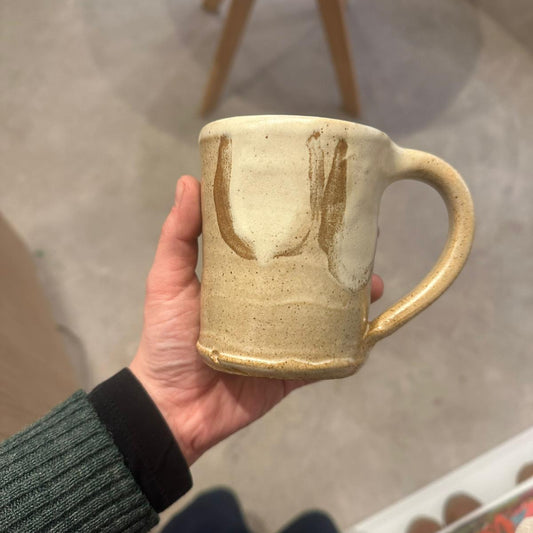 Hand holding a ceramic mug outdoors on a concrete surface