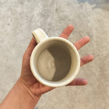 Load image into Gallery viewer, Hand holding a white mug with a blurred background
