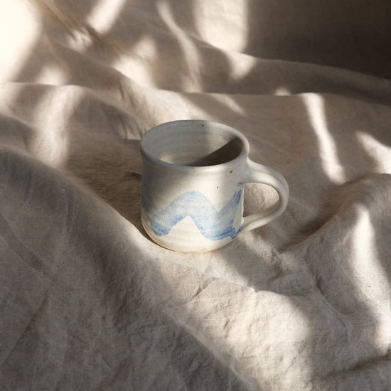 Ceramic mug with blue design on a textured beige surface