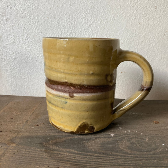 Yellow ceramic mug with brown accents on a wooden surface