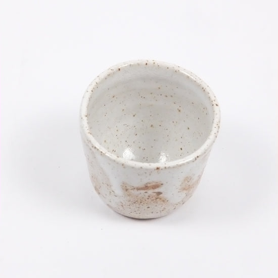 White ceramic cup with speckled texture on a white background