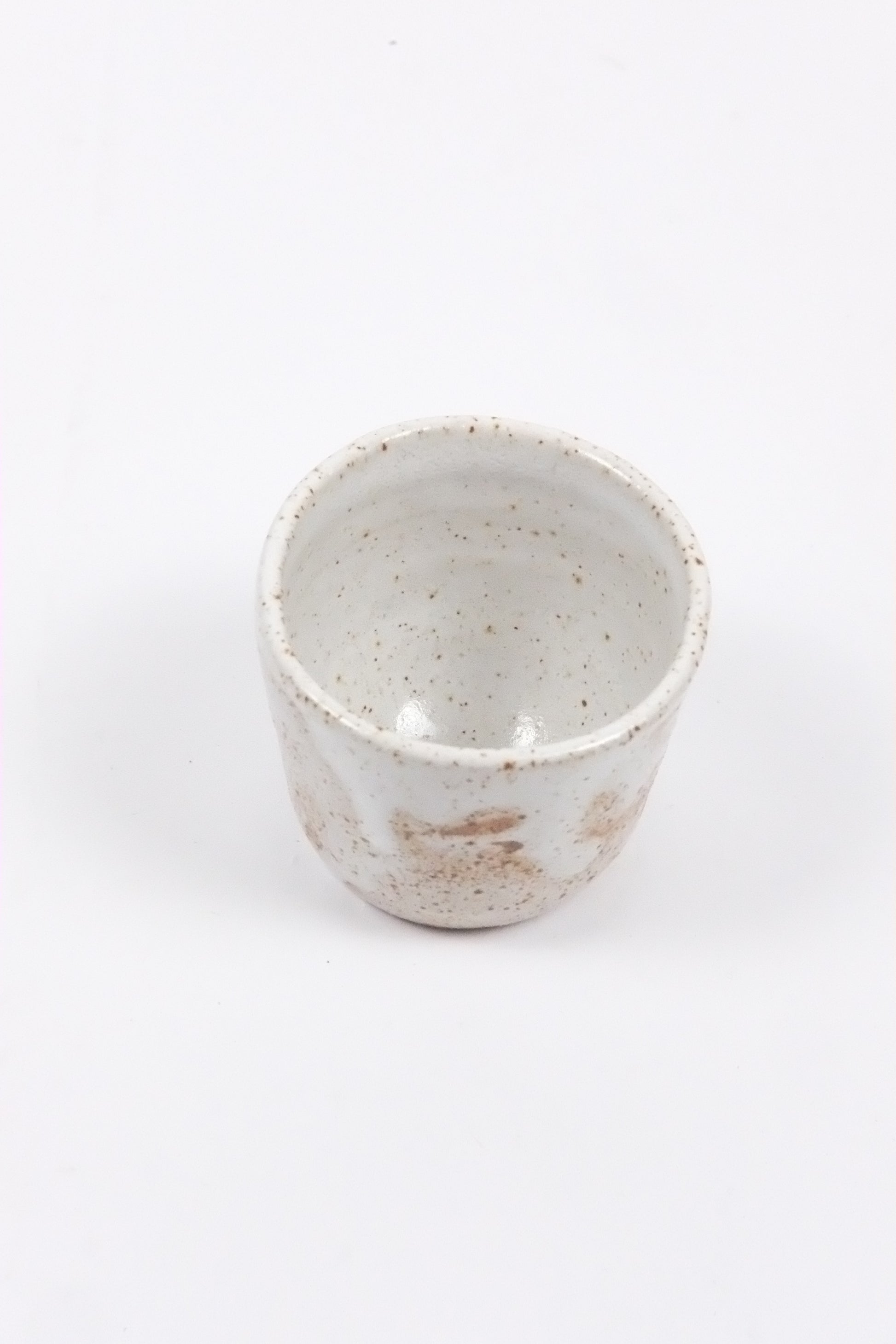 White ceramic cup with speckled texture on a white background