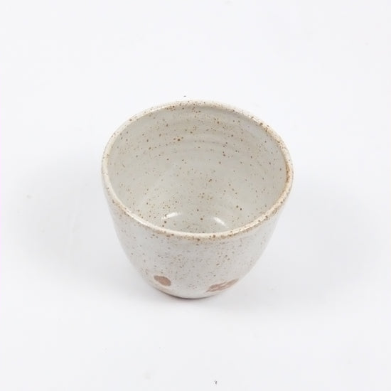 Speckled ceramic cup on a white background