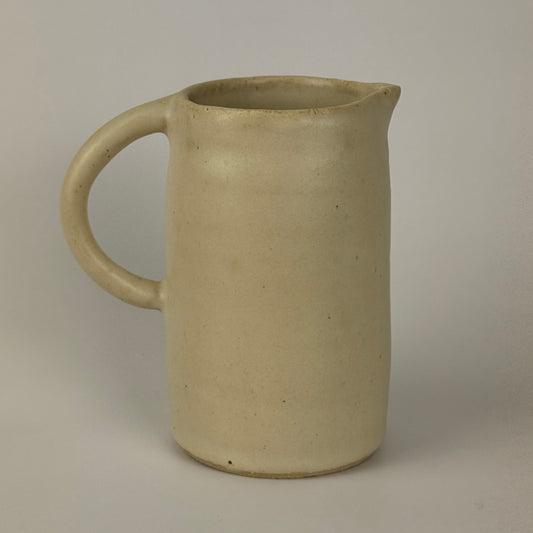 Beige ceramic pitcher on a plain background
