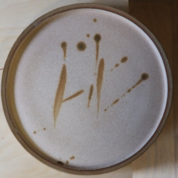 Ceramic plate with brown abstract design on a wooden surface