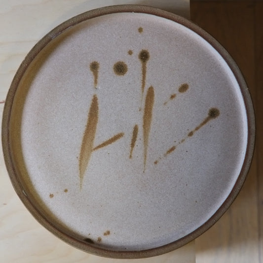 Ceramic plate with brown abstract design on a wooden surface