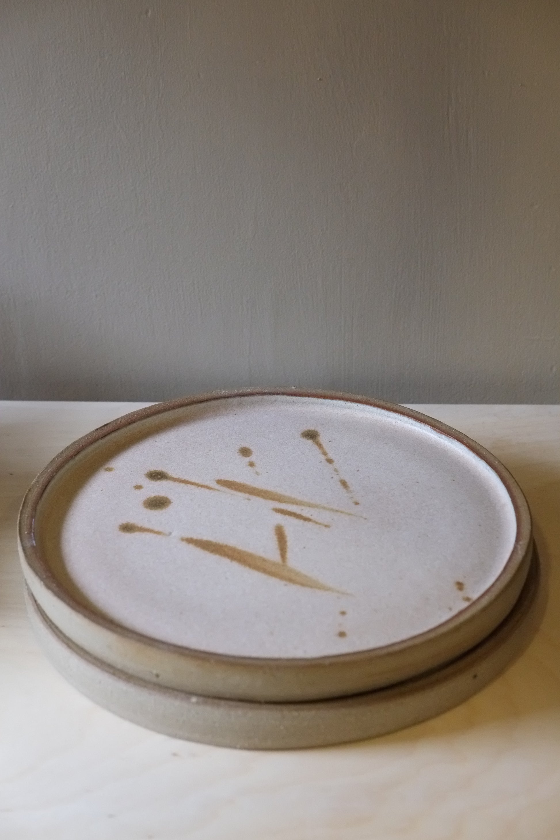 Close-up of a ceramic plate with a signature on a neutral background