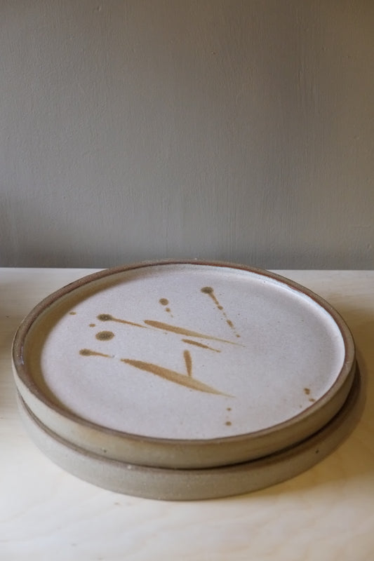 Close-up of a ceramic plate with a signature on a neutral background