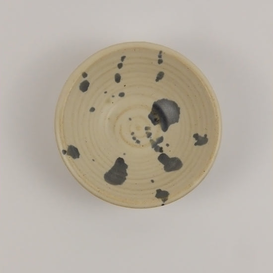 Ceramic bowl with black speckles on a gray background