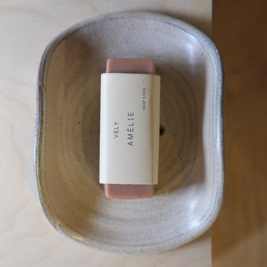 Bar of soap with a label in a ceramic dish on a wooden surface
