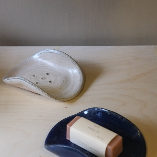 Two ceramic items, one white and one blue with a brown handle, on a wooden surface.