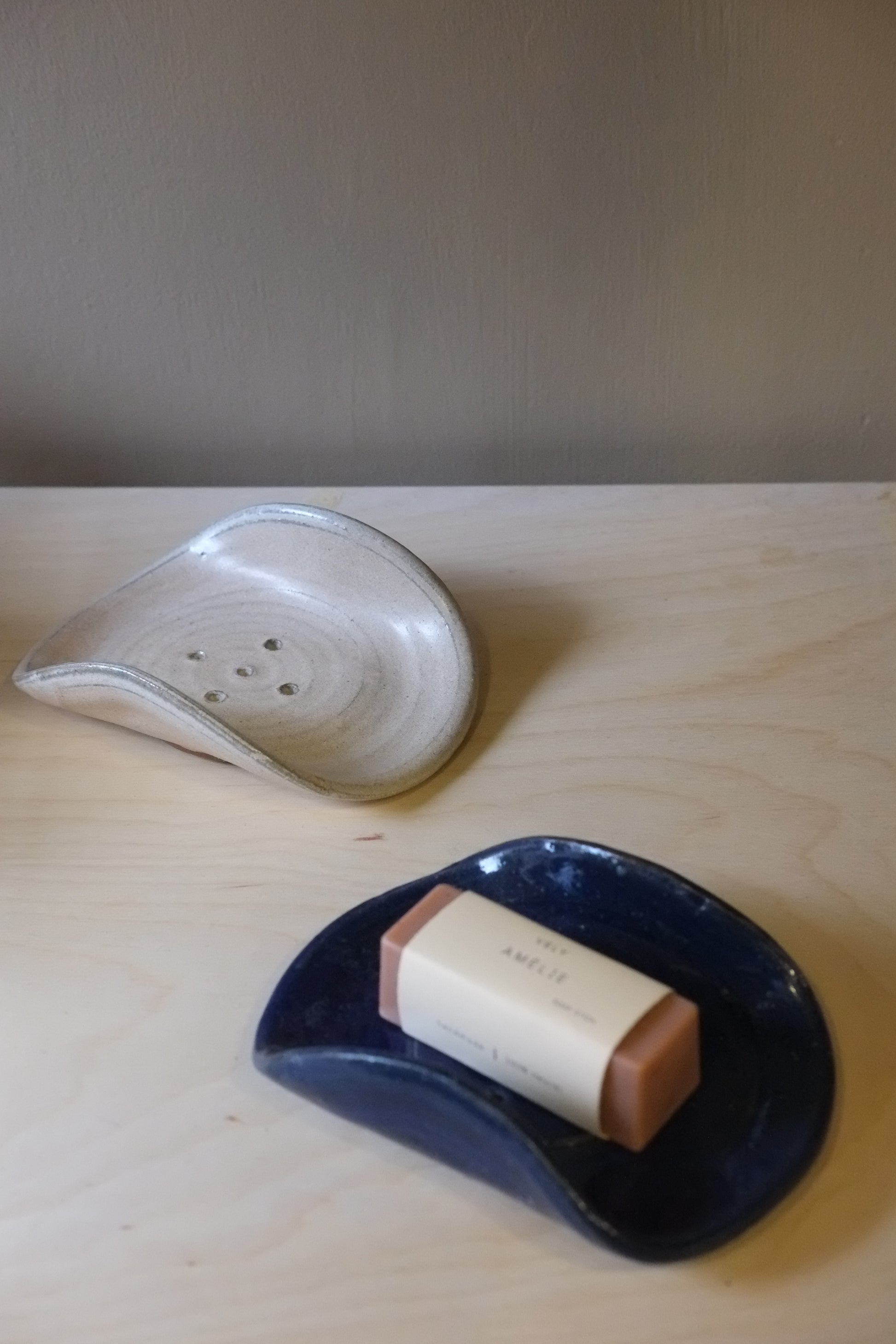 Two ceramic items, one white and one blue with a brown handle, on a wooden surface.