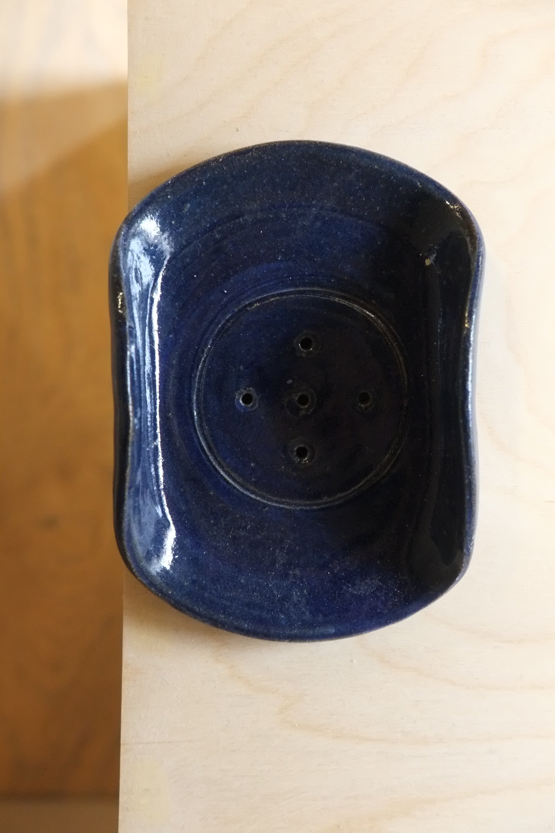 Blue soap dish with multiple holes on a wooden surface