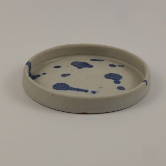 Round ceramic plate with blue splotches on a white background