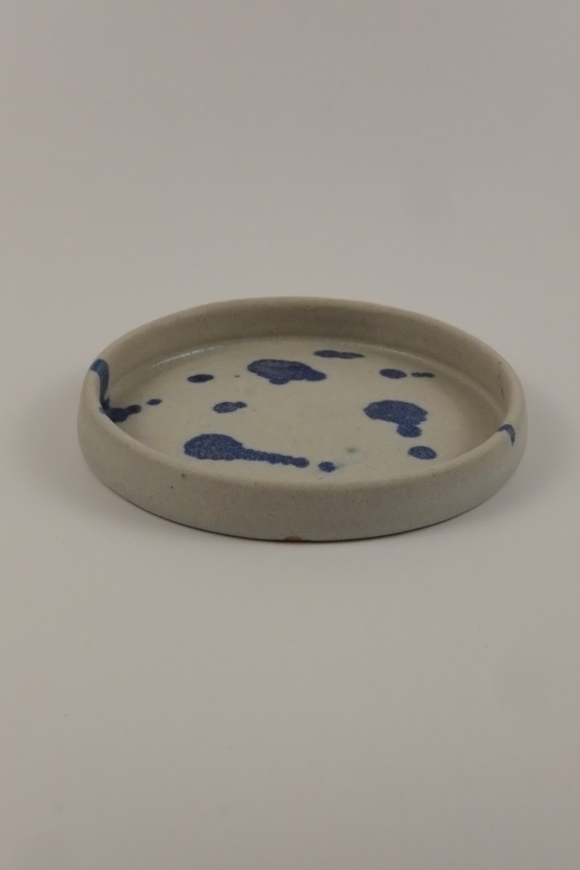 Round ceramic plate with blue splotches on a white background