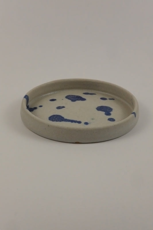 Round ceramic plate with blue splotches on a white background
