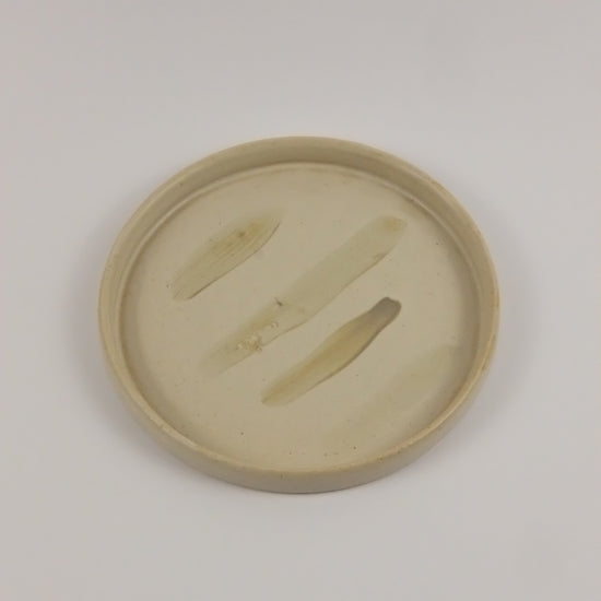 Round beige object with cut-out design on a light gray background