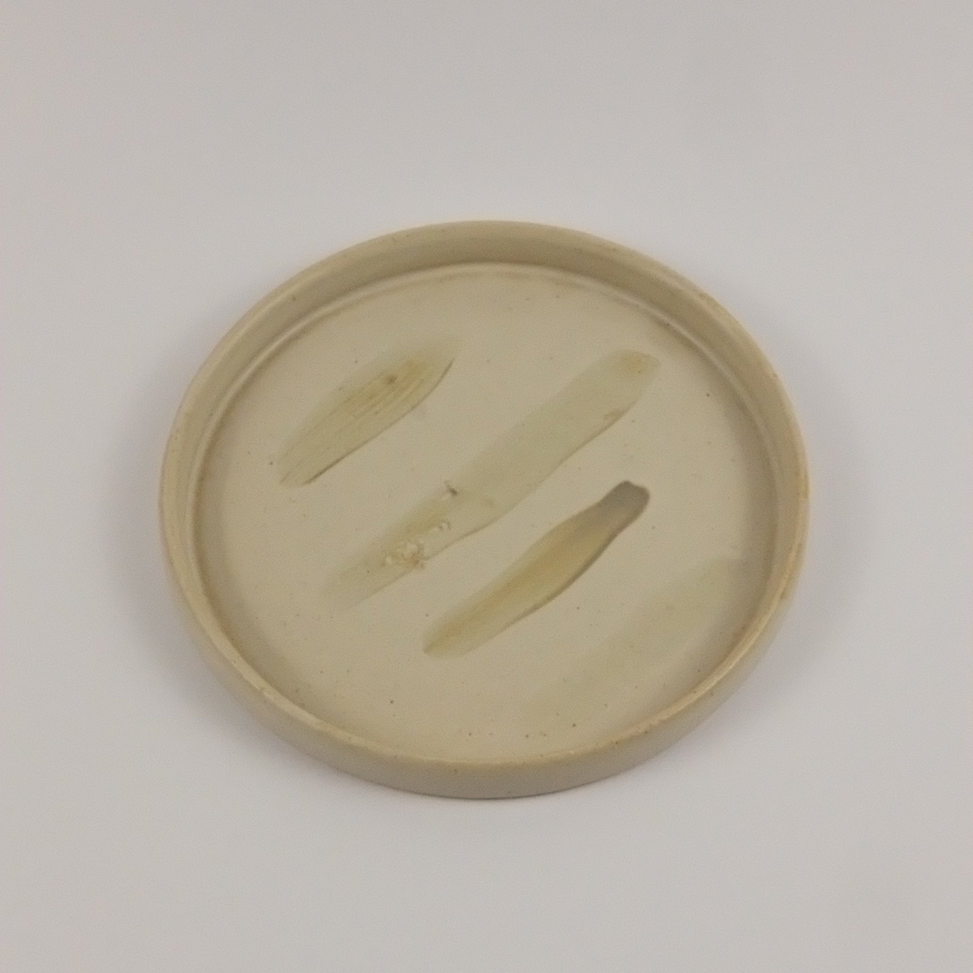 Round beige object with cut-out design on a light gray background