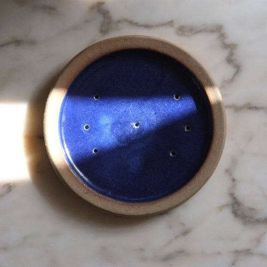 Round blue object with gold rim on a marble surface