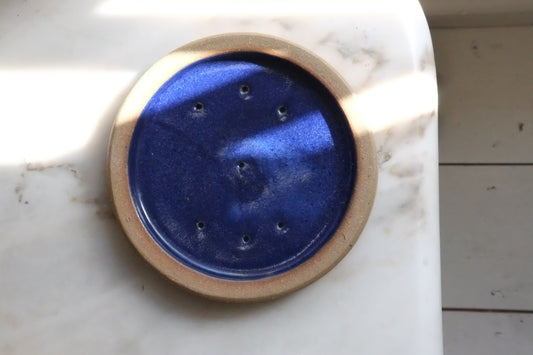 Round blue ceramic object with wooden rim on a marble surface