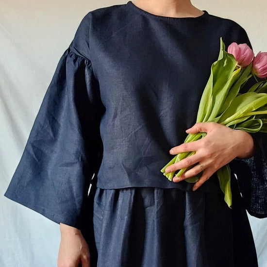 Woman in a dark blue dress holding pink tulips against a white background