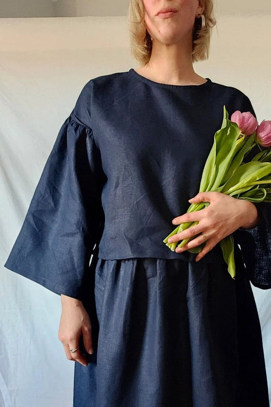 Woman in a dark blue dress holding pink tulips against a white background