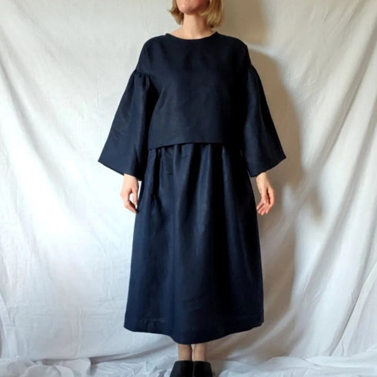 Person wearing a dark blue dress standing against a white backdrop