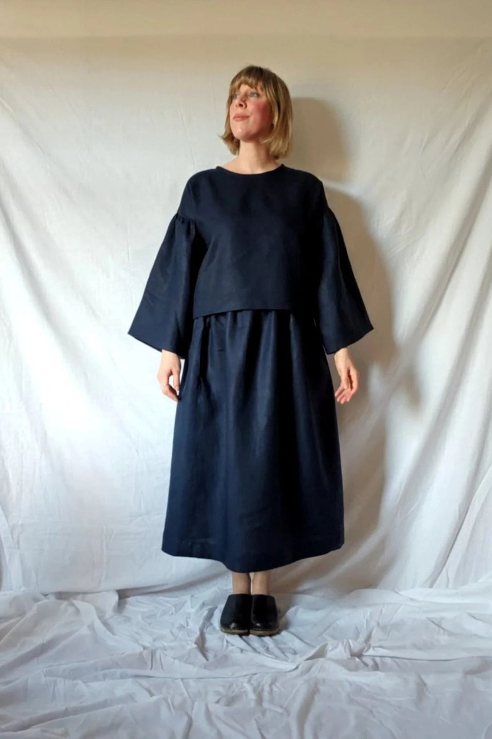Person wearing a dark blue dress standing against a white backdrop