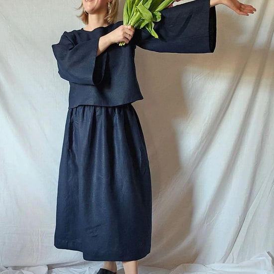 Person wearing a navy blue outfit holding pink tulips against a white backdrop