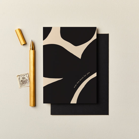 Black and beige card with gold pen and stamp on a light background