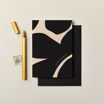 Black and beige card with gold pen and stamp on a light background