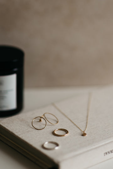 Gold jewelry including rings and a necklace on an open book with a blurred background