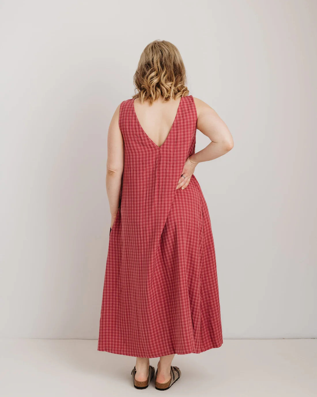 Woman wearing a pink checkered dress against a white background