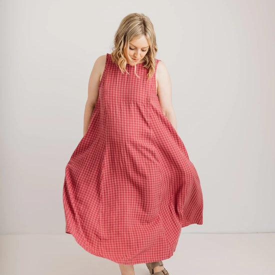 Woman wearing a pink checkered dress against a white background