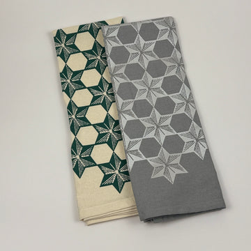 Two folded towels with geometric patterns on a light gray background