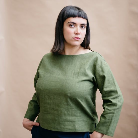 Woman wearing a green sweater against a beige background