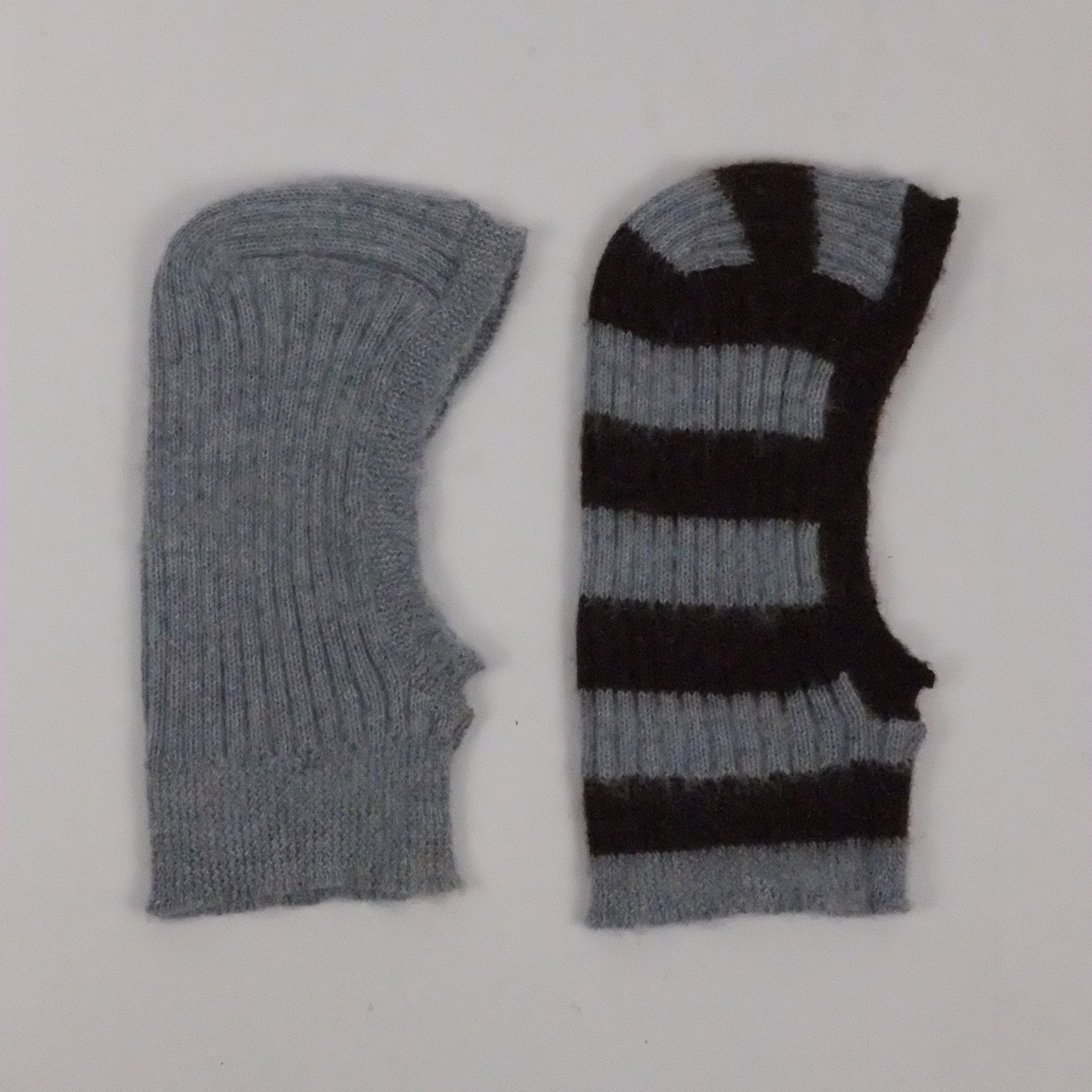 Two knitted balaclava, one gray and one black and gray striped, on a white background.