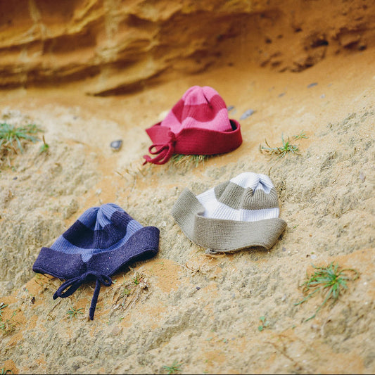 three hats  in various colours hats on a dune