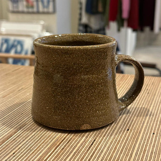 Brown ceramic mug on a wooden table with a blurred indoor background